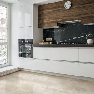 The interior of the beautiful trendy modern kitchen with white furniture, wooden inserts, combined wooden and mosaic floors and a large floor-to-ceiling window.